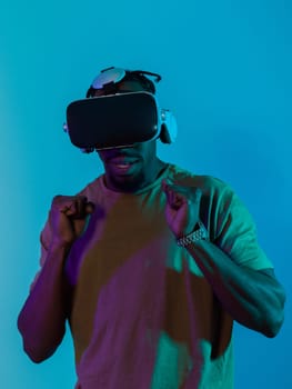 African American man immerses himself in a thrilling horror gaming experience using VR glasses, creating an isolated and intense atmosphere against a striking blue background.