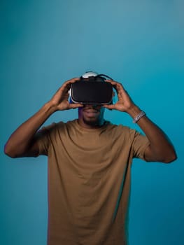 In a futuristic visual, an African American man stands isolated against a striking blue backdrop, adorned with VR glasses that transport him into a cutting-edge virtual reality experience, merging technology and innovation in a contemporary display.