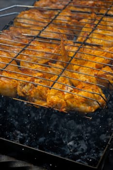 Delicious chicken frying on barbecue grill grate outdoor. Seasoning falling on fresh grilled chicken wings. Summer party food ideas. BBQ Juicy roasting chicken grill legs on grill grate