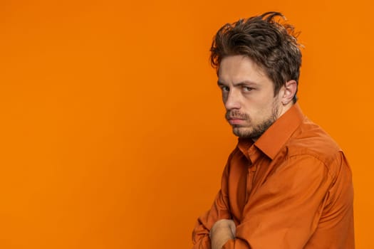 Offended sad nervous Caucasian man having misunderstanding, frustrated after quarrel, fail, lose, ignores and does not want to communicate, talk. Bearded guy isolated on orange background. Copy-space