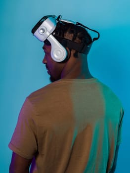 In a futuristic visual, an African American man stands isolated against a striking blue backdrop, adorned with VR glasses that transport him into a cutting-edge virtual reality experience, merging technology and innovation in a contemporary display.