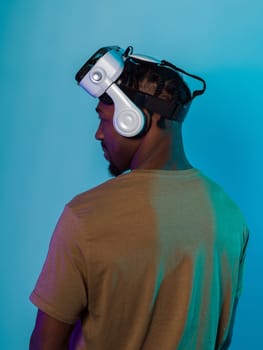 In a futuristic visual, an African American man stands isolated against a striking blue backdrop, adorned with VR glasses that transport him into a cutting-edge virtual reality experience, merging technology and innovation in a contemporary display.