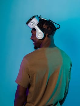 In a futuristic visual, an African American man stands isolated against a striking blue backdrop, adorned with VR glasses that transport him into a cutting-edge virtual reality experience, merging technology and innovation in a contemporary display.