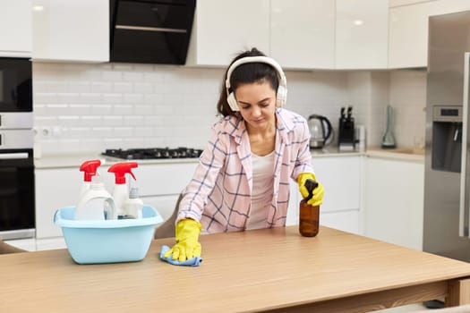 young woman in gloves cleaning and wiping wooden table with microfiber cloth. chores at home. Housekeeping