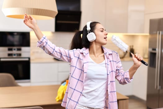 young happy housewife woman singing and cleaning her home, girl enjoying domestic work.