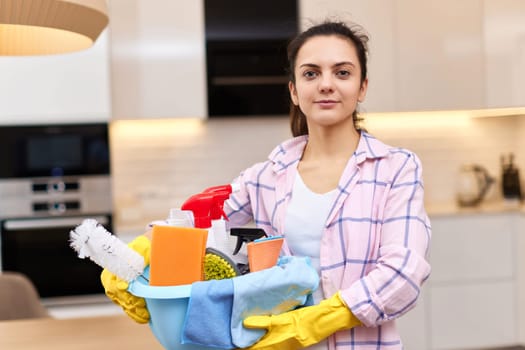 Woman in rubber protective yellow gloves holding cleaning tools. house chores.