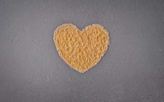 Top view of golden powder heart shape on gray background with copy space.