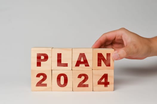 Hand place wooden cubes with PLAN 2024 on white background. Business plan, goals and strategy concept.