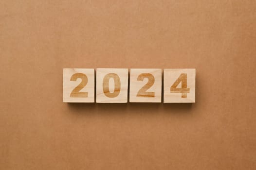 Wooden cube blocks with 2024 on brown background. Start new year goals, plan and visions concept.