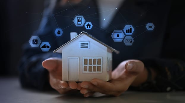 Hands holding small house model with with icons. Innovation technology and smart home concept.