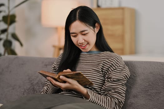 Pretty young woman resting on comfortable couch and reading book. Hobbies, domestic life and lifestyle concept.