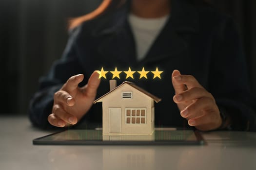 Businesswoman showing 5 stars rating with home model. Real estate appraisal concept and excellent service concept.