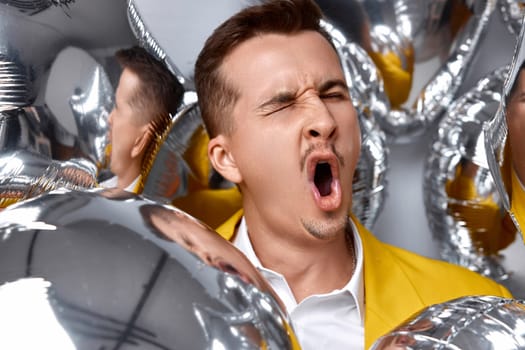 guy with a lot of silver air balloons fooling around at birthday party