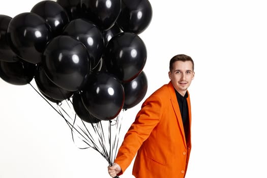 happy man in orange jacket with black air balloons on white background. birthday party