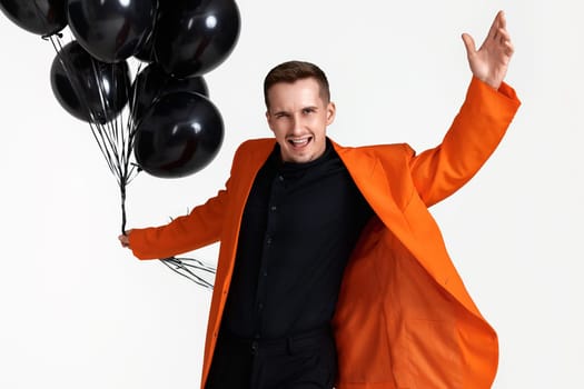 very excited guy in orange jacket with black air balloons on white background. birthday party