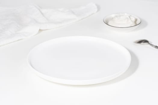 Empty white plate on a white table.