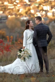 beautiful bride in white wedding dress and groom enjoying romantic moments on natural background