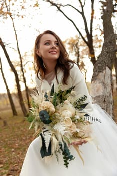 beautiful happy bride holding wedding autumn bouquet in nature