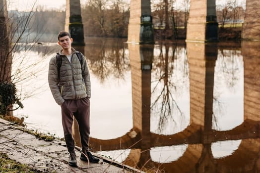 Youthful Exploration: 17-Year-Old Teen in Stylish Jacket by Neckar River and Historic Bridge in Bietigheim-Bissingen, Germany. Capture the essence of seasonal charm as a 17-year-old teenager stands confidently by the picturesque Neckar River, adorned in a fashionable jacket, against the backdrop of the historic bridge pillars in the city of Bietigheim-Bissingen, Germany. This captivating image blends youthful style with cultural heritage, offering a glimpse into the unique blend of modern fashion and historical architecture, creating an enchanting scene of urban exploration during the autumn or winter season.