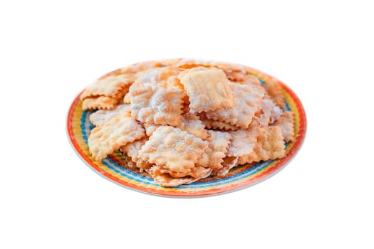 Traditional sweet crisp pastry deep-fried and sprinkled with powdered sugar on multicolored plates isolated on white. Carnival food tradition. Italy