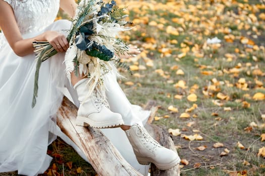 bride wearing white boots holding beautiful autumn bouquet. copy space