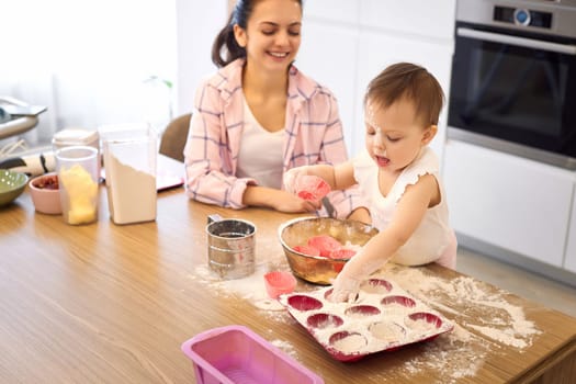 mother and little baby girl preparing the dough in the kitchen, bake cookies. happy time together