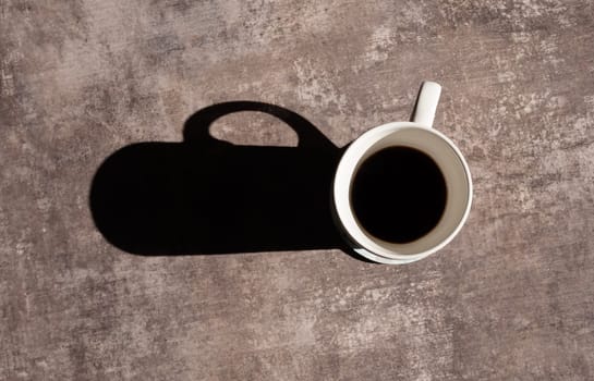 white coffee cup on a wooden desk with shadow.