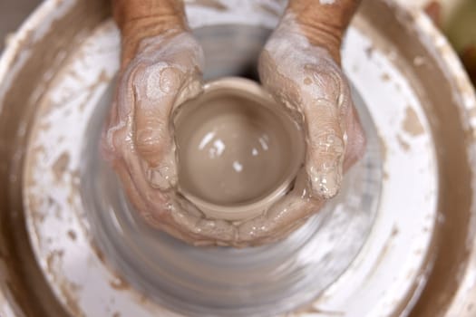 male hands making ceramic cup on pottery wheel, Close-up, top view