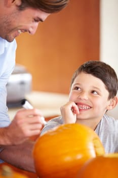 Halloween, pumpkin and father with kid in the kitchen for holiday celebration at home. Creative, smile and happy dad with boy child bonding and carving vegetable for decoration or tradition at house