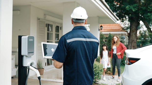 Qualified technician working on home EV charging station installation, making troubleshooting and configuration setup on charging system with empty laptop screem for EV at home. Synchronos