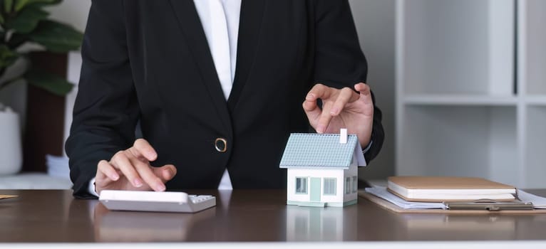 Female real estate agent is calculating the budget before signing a contract for a real estate project with a house model