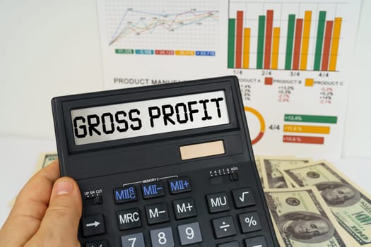 Business concept. On the table there are financial reports, dollars, in the hands of a calculator with the inscription - gross profit