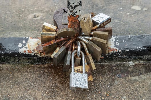 France, Paris - Jan 02, 2024 - Many love padlocks locked on rusty metal handle on a rainy day. Love locks attached together for love wishes, Symbol of constant love and durability of the relationship, Crowded Love Padlocks and romance concept, Space for text, selective focus.