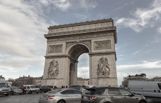 France, Paris - Jan 03, 2024 - Famous Arc de Triomphe (Triumphal Arch) at the city center of Paris and traffic trails in Chaps Elysees. Symbol of the glory and historical heritage, Iconic touristic architectural landmark, Tourism and travel concept, Space for text, Selective focus.