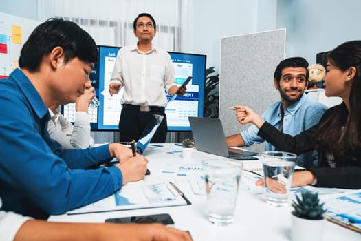 Project manager communicate and collaborate with team using project management software display on monitor, tracking progress of project task and making schedule plan at meeting table. Prudent