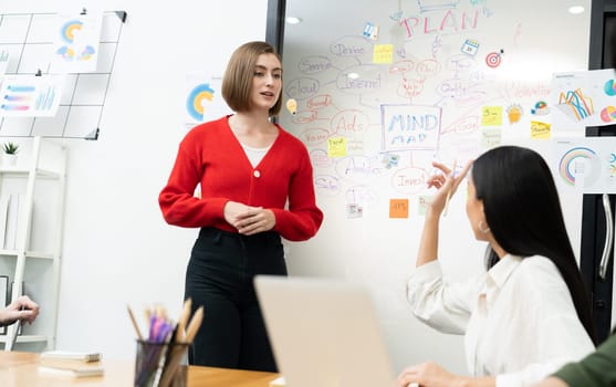 Professional attractive female leader presents creative marketing plan by using brainstorming mind mapping statistic graph and colorful sticky note at modern business meeting room. Immaculate.