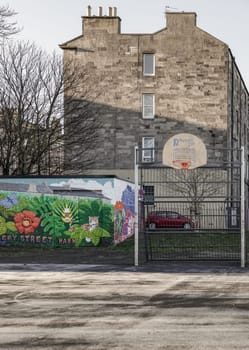 Edinburgh, Scotland, Jan 17, 2024 - Basketball backboard with the orange hoop metal ring at outdoor basketball courts in the park against old buildings background in the city downtown. Space for text, Selective focus.
