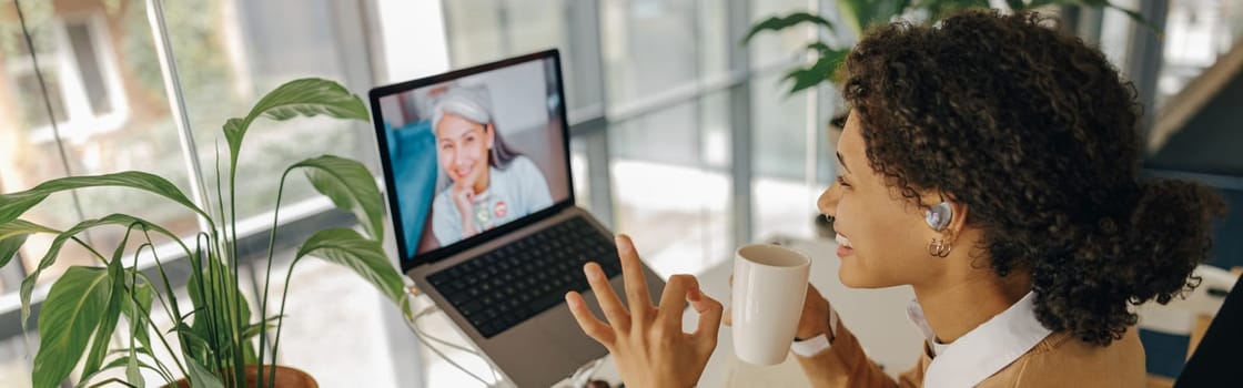 Female freelancer have video conference with client and showing sign Ok sitting in cozy coworking