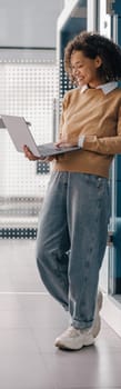 Stylish business woman using laptop while standing on modern office background