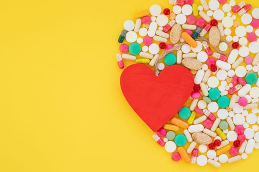 Heart and colorful pills on red background