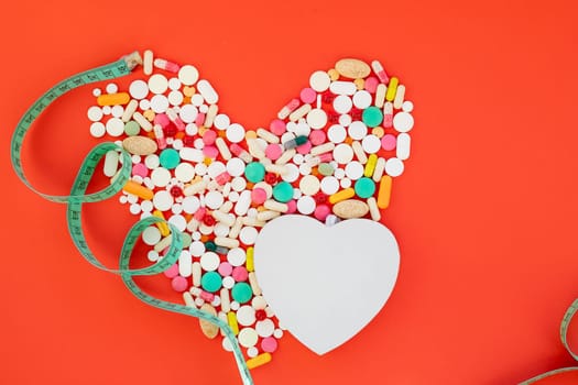 Danger for heart, medication,many colorful pills, capsules on red background.OBESITY concept.