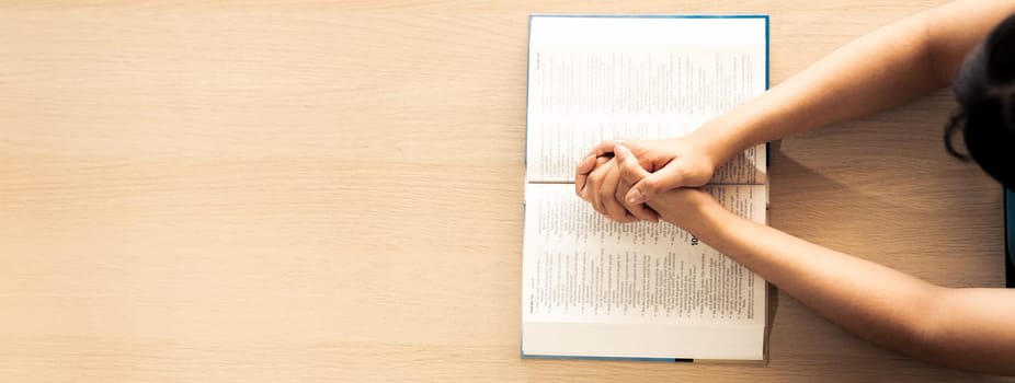 Female prayer folding hand on holy bible book on wooden church table. Concept of hope, religion, faith, christianity praying for love and god blessing. Warm and brown background.Top view. Burgeoning.
