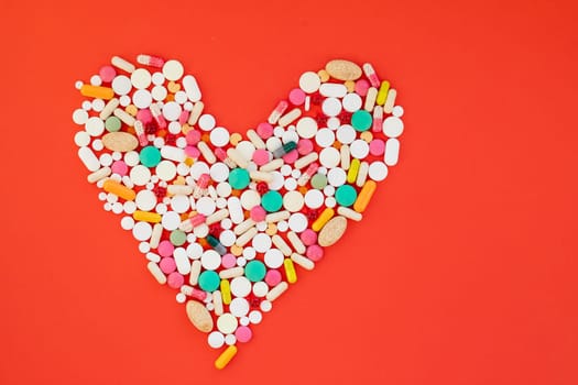 Danger for heart, medication,many colorful pills, capsules on red background.OBESITY concept.