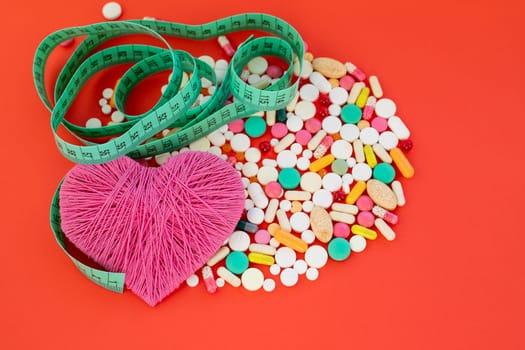 Danger for heart, medication,many colorful pills, capsules on red background.OBESITY concept.
