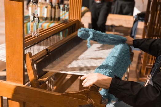 Master weaver is weaving the tapestry with diverse bright threads, close up. Artisanal at work.