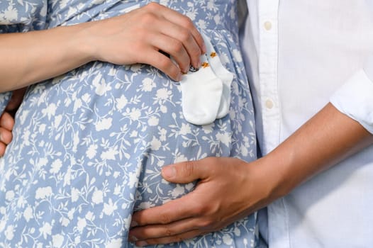 A family couple hugs a pregnant woman's belly, a man and a woman are expecting a baby, a photo session for pregnant women.