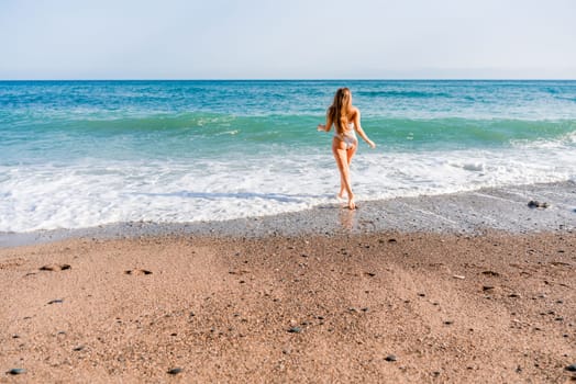 Happy woman in bikini running on the beach. Active leisure, a beautiful girl in a bikini is having fun on the beach, big waves are splashing along the beach