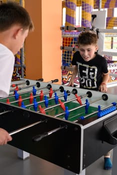Two boys in the game room playing table football, mental and active recreation.
