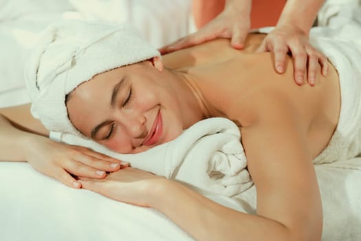 Beautiful caucasian woman having back massage by Thai professional masseur. Attractive woman feel deep in relaxation surrounded by aroma and essential oil. Relaxing and calm concept. Tranquility.