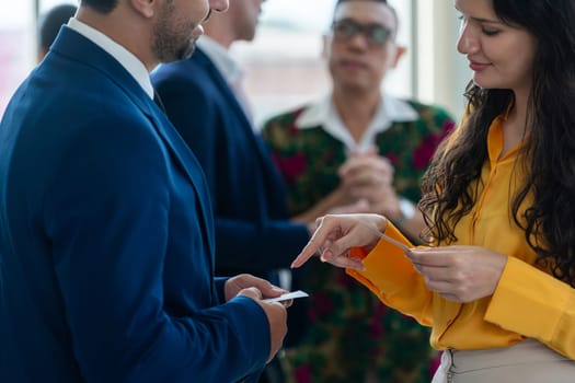 Successful businesswoman holding the name card during talking to manager about their cooperation. Cropped image of exchanging name card between businessman and businesswoman. Side view. Intellectual.